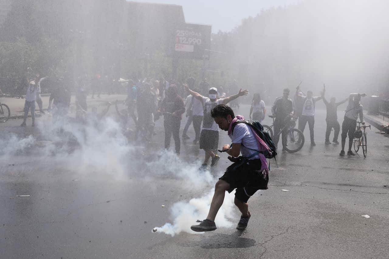A protester kicks a tear gas canister during clashes with police in Santiago, Chile.