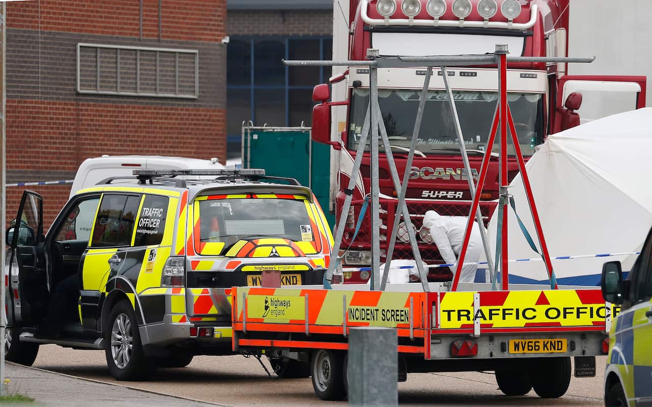 Police forensic officers attend the scene after a truck, in rear, was found to contain 39 bodies, in Thurrock, South England.