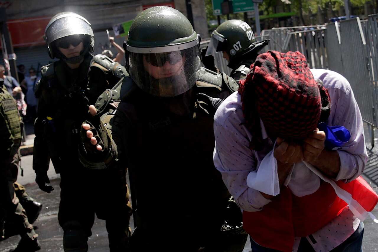 A policeman escorts an injured protester on the sixth day of protests against the Government, in Santiago, Chile.