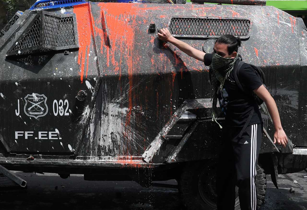 A demonstrator walks up to a police armored vehicle during clashes in Santiago, Chile.