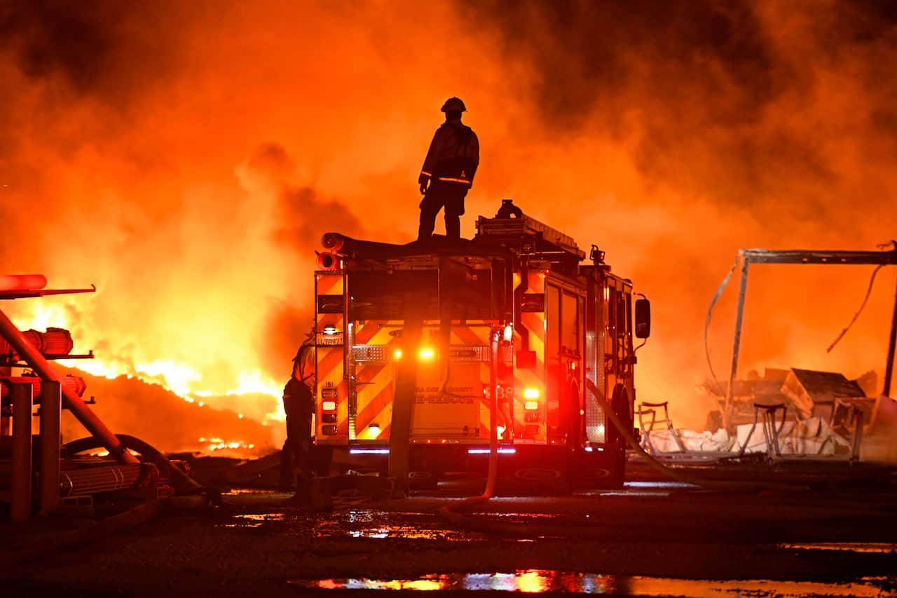 A firefighter stops to look at a wall of fire while battling a grass fire on East Cypress Road in Knightsen, California on Sunday, October. 27, 2019
