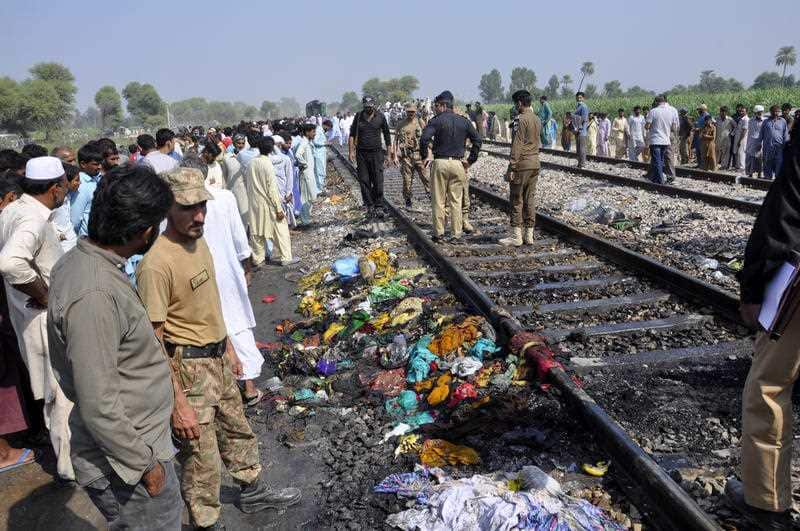 Pakistani soldiers and officials examine the train damaged by a fire in Liaquatpur