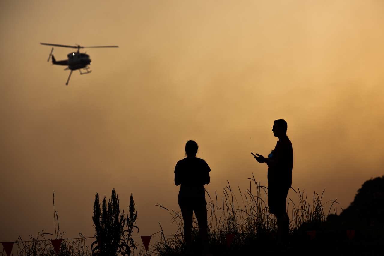 A water bombing helicopter is seen through a smoke haze in Forster, NSW mid-north coast.