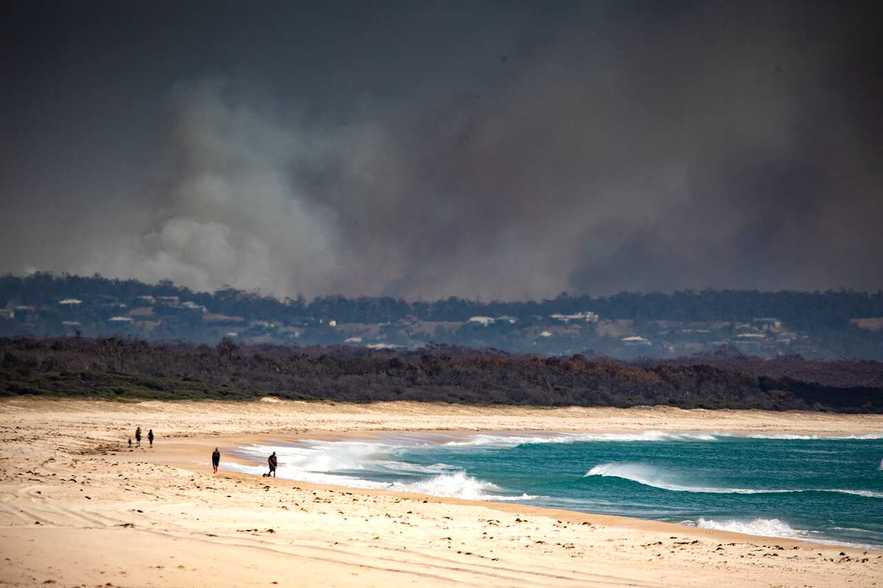 Smoke is seen in the distance near Tuncurry, NSW, November 9, 2019. At least 100 homes have been lost in NSW's North, with about 80 fires still burning around the state. (AAP Image/Shane Chalker) NO ARCHIVING