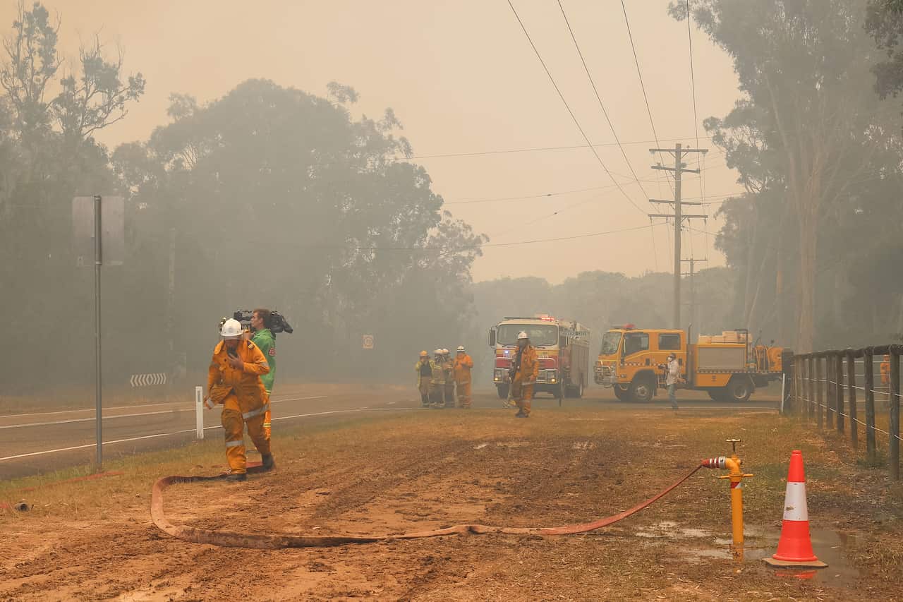Firefighters and helicopters tackle the fires at Lake Cooroibah Road and Jirrimah Crescent in Cooroibah in Noosa Shire.