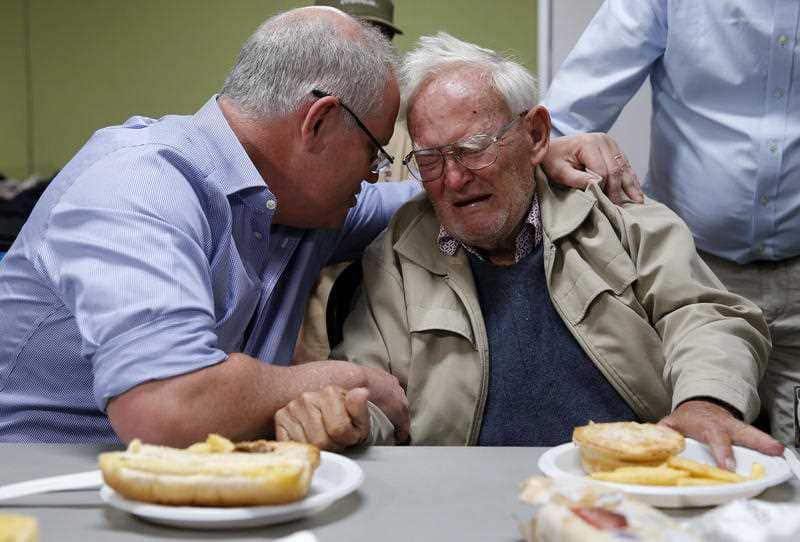 Prime Minister Scott Morrison is seen comforting a man who has been evacuated from his home during a visit to Taree, New South Wales