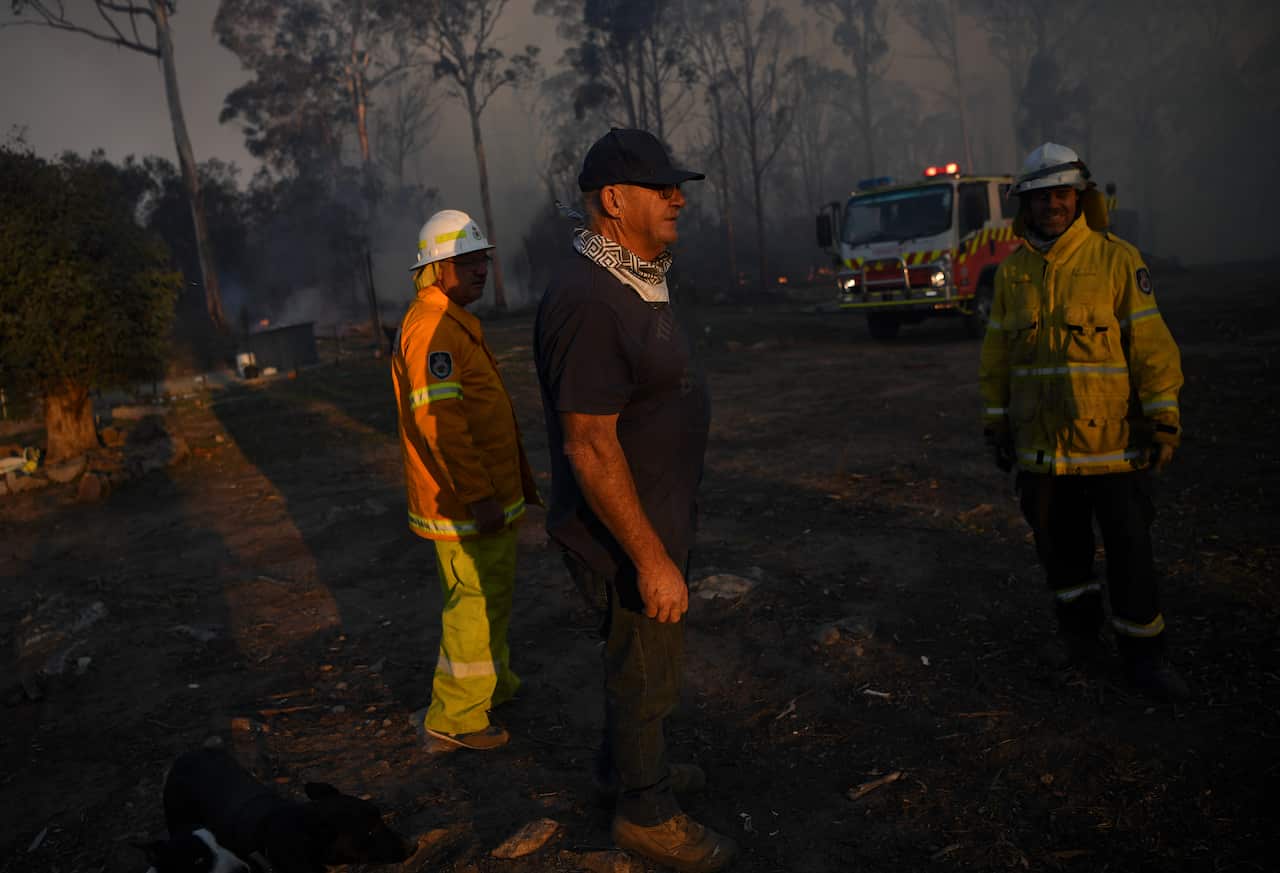 Geoff Hilton (centre) chats to volunteer firefighters who successfully defended his property in Torrington, near Glen Innes.