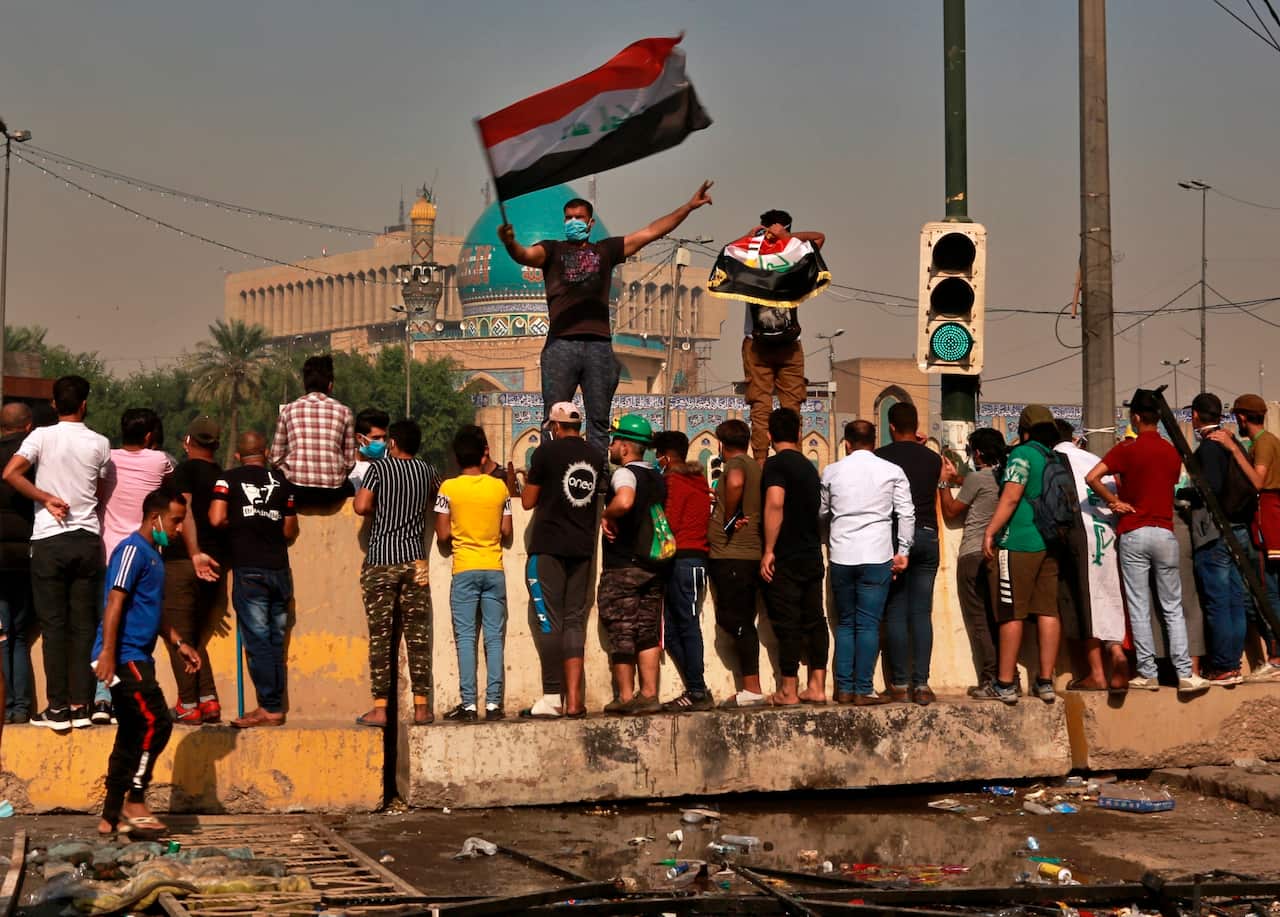 Anti-government protesters stand on concrete barriers placed by security forces, during clashes with security forces, in downtown Baghdad, Iraq, Sunday, Nov. 10, 2019. (AP Photo/Khalid Mohammed)