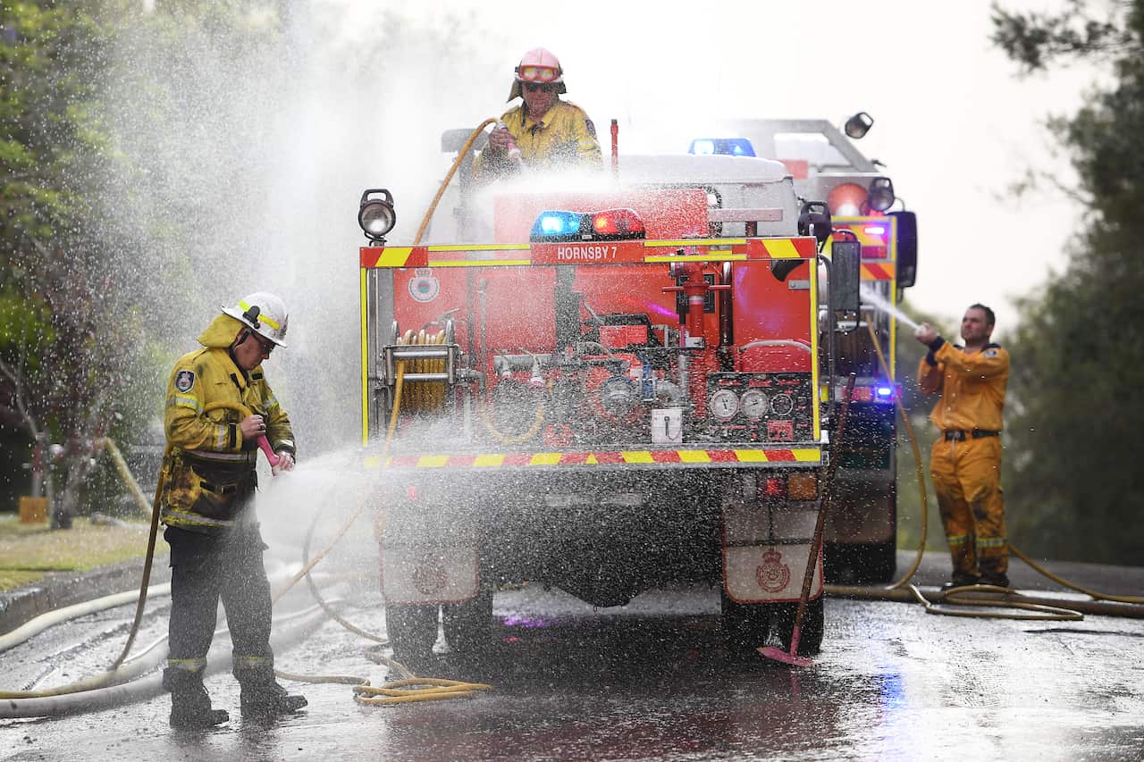 NSW Rural Fire Service crews wash chemical fire retardant off their truck after it was dropped to protect houses at South Turramurra, north of Sydney.