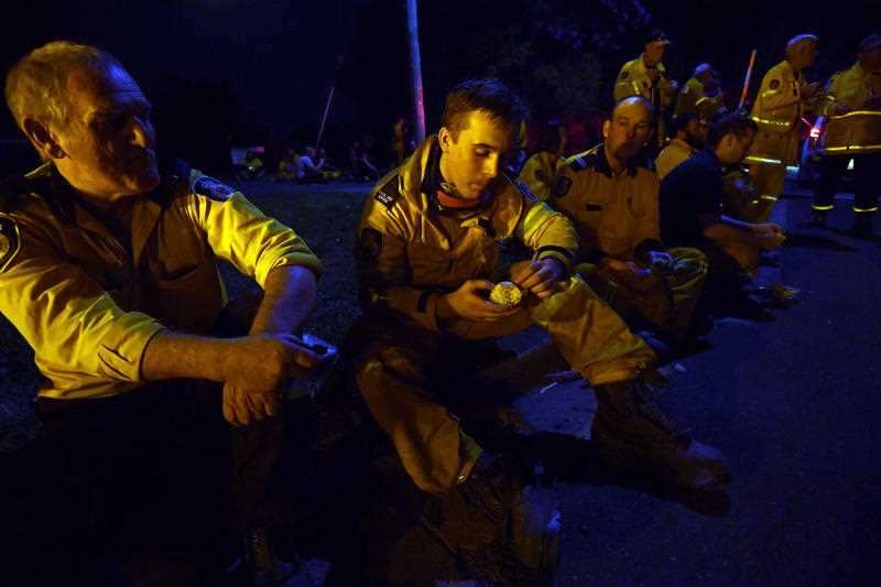 Weary firefighters take a break from battling bushfires in Nana Glen, near Coffs Harbour