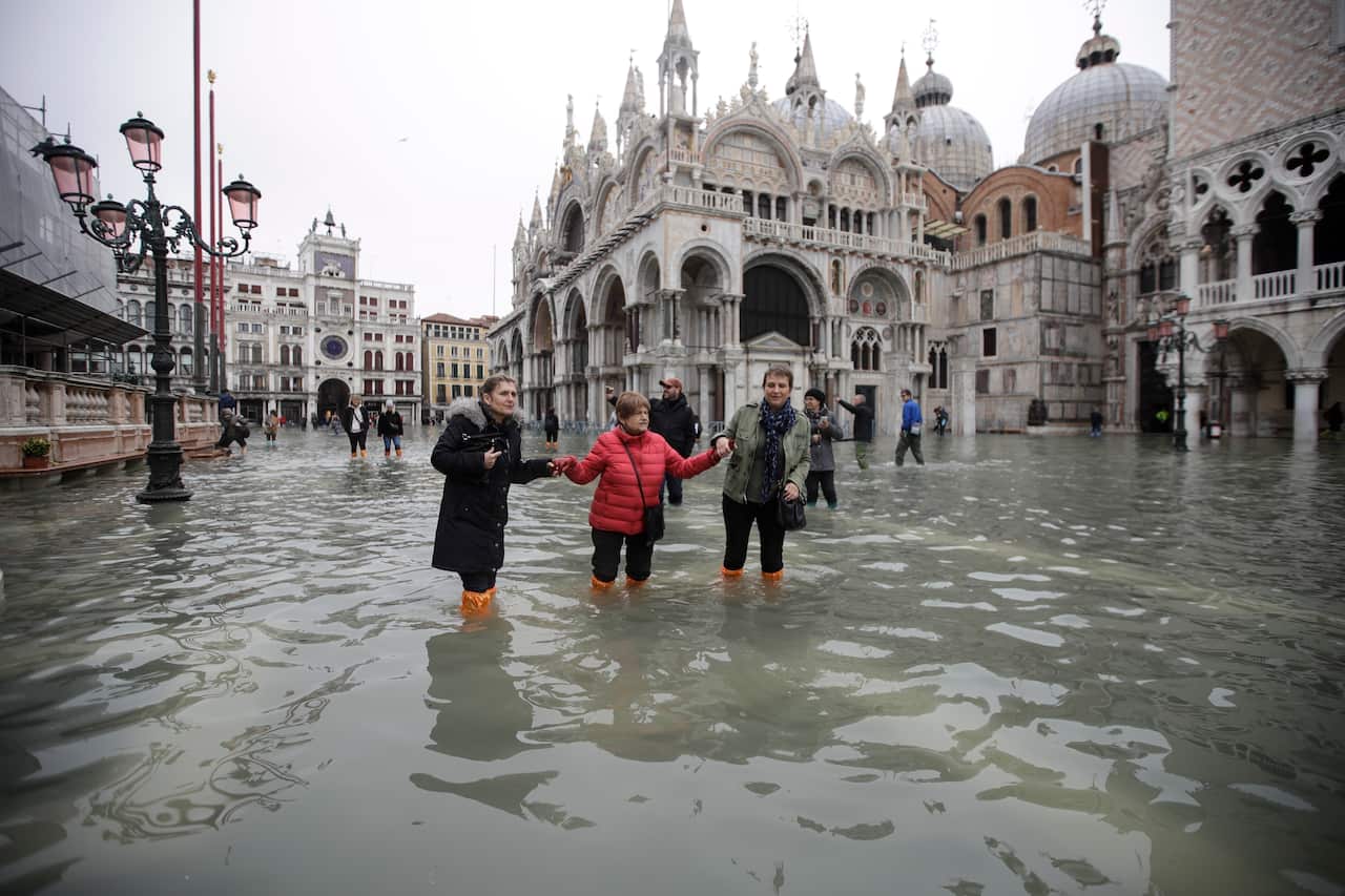 People wade through water in a flooded St. Mark's Square in Venice.