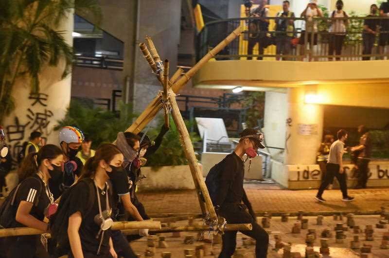 Protesters carry a hand-made catapult for fighting against the police during a protest at Hong Kong Baptist University