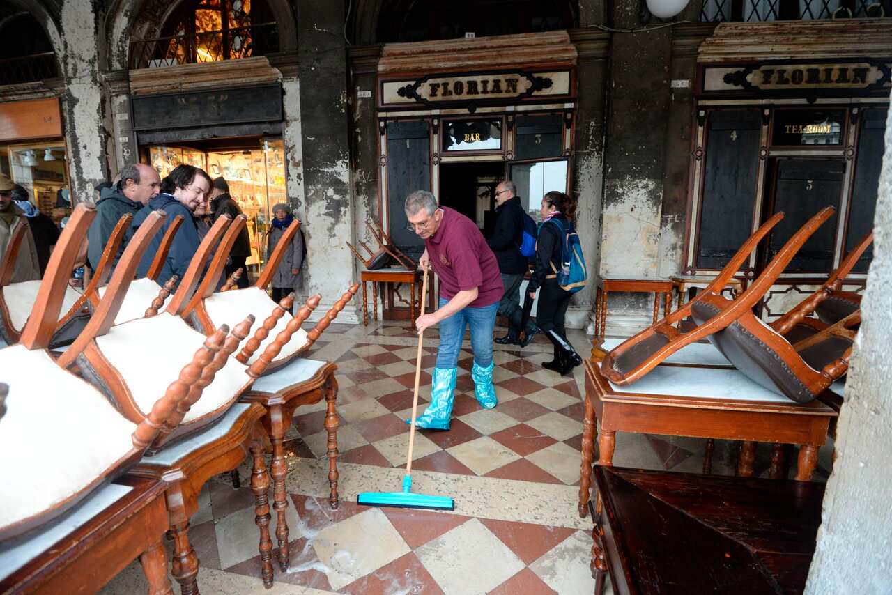 A man cleans water out of the historical Florian cafe.