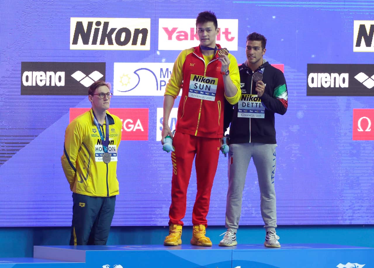 China's Sun Yang holds up his gold medal as silver medalist Australia's Mack Horton, left, stands away from the podium at the World Swimming Championships.
