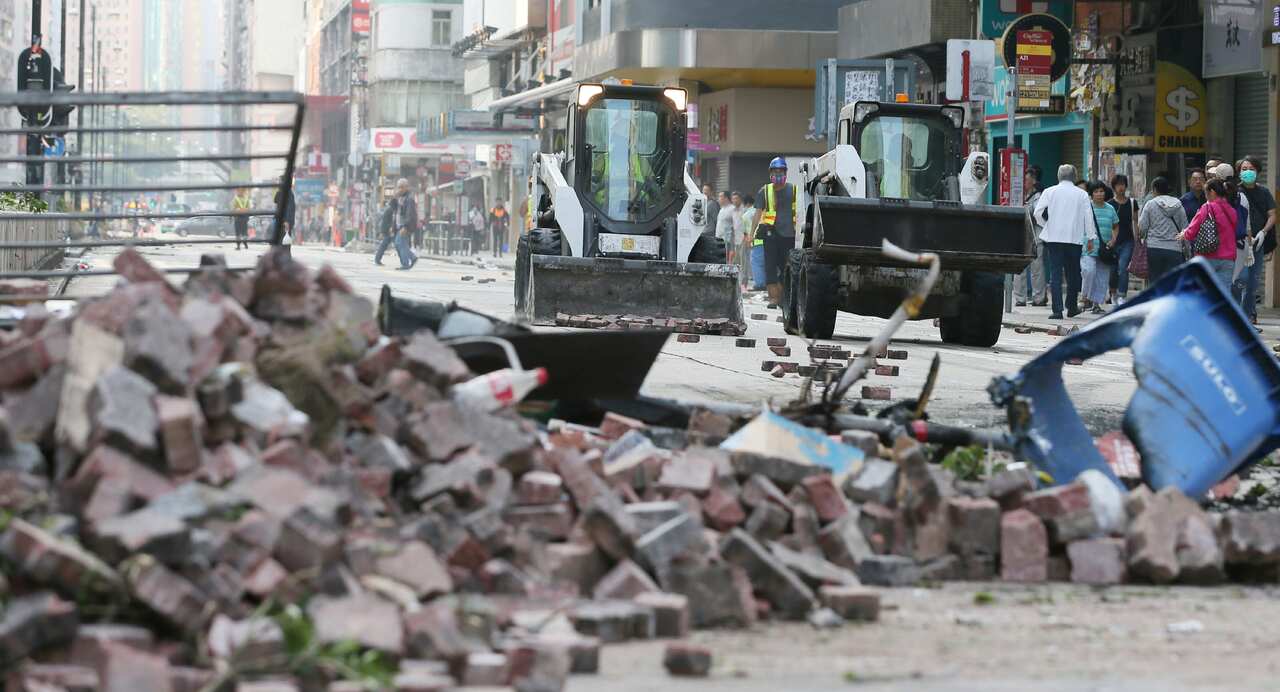 Workers remove debris which protesters set on the road in Hong Kong.
