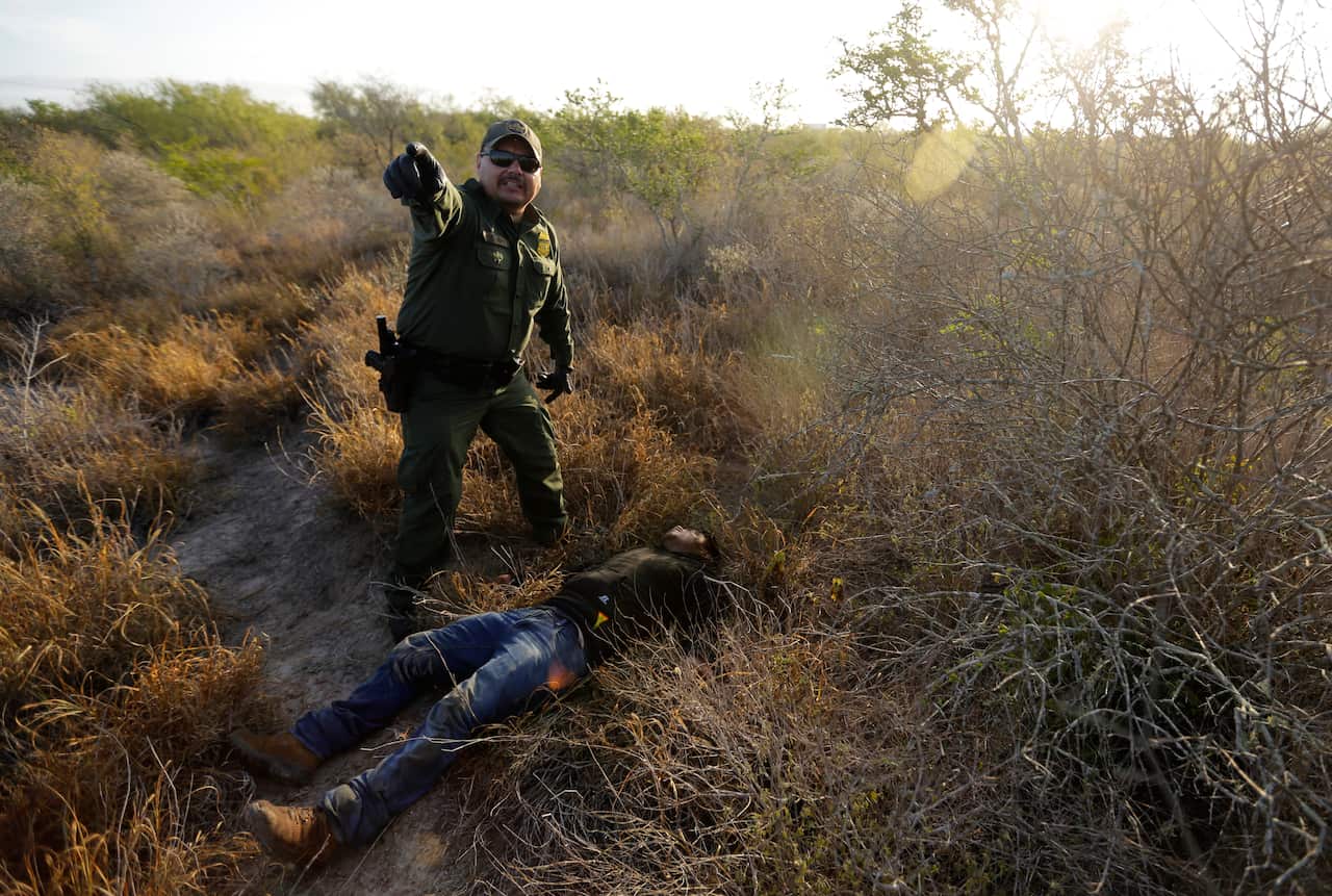 A Border Patrol agent stops a man thought to have entered the country illegally along the US-Mexico border.