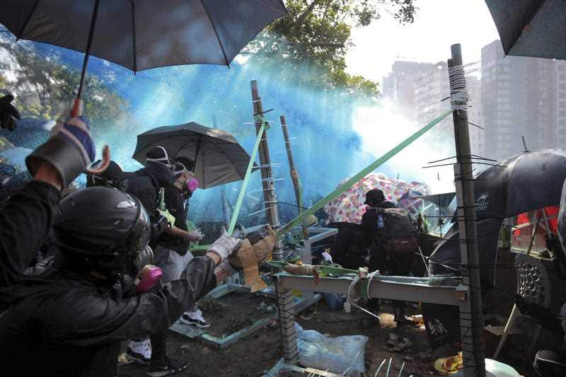 Protestors use an improvised slingshot as blue-dyed liquid is sprayed from an armored police vehicle during a confrontation at Hong Kong Polytechnic University