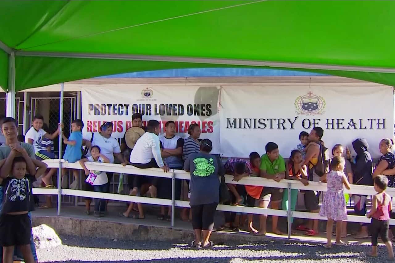 Children with parents wait in line to get vaccinated outside a health clinic in Apia, Samoa.