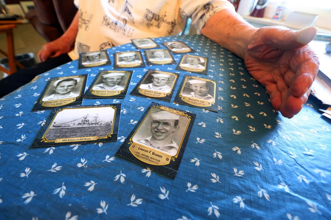 Lauren Bruner poses with cards showing the ship and some of his shipmates.