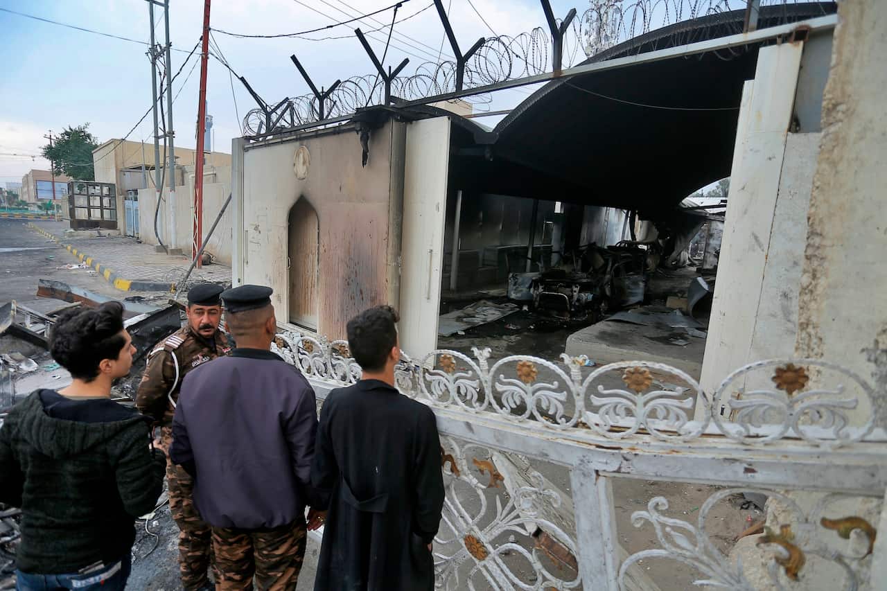 Security force and civilians gather near the burned Iranian consulate in Najaf, Iraq.