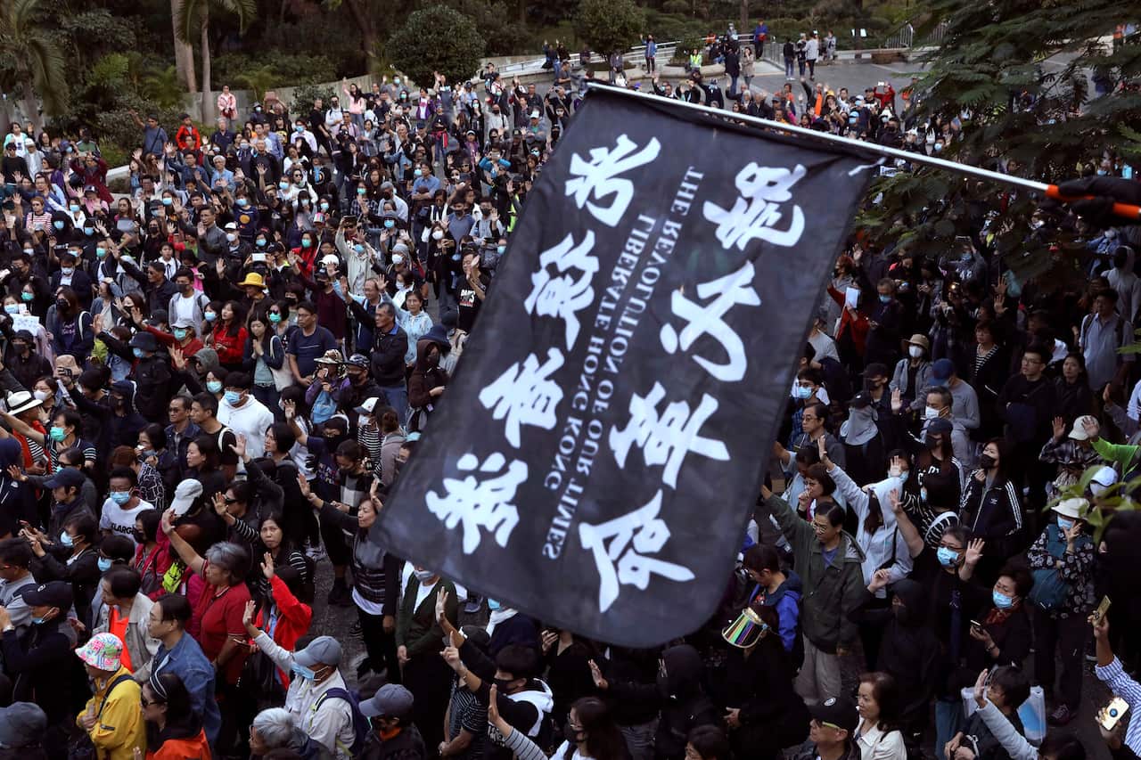 A protester waves a flag reading 'Liberate Hong Kong, the Revolution of Our Times'.