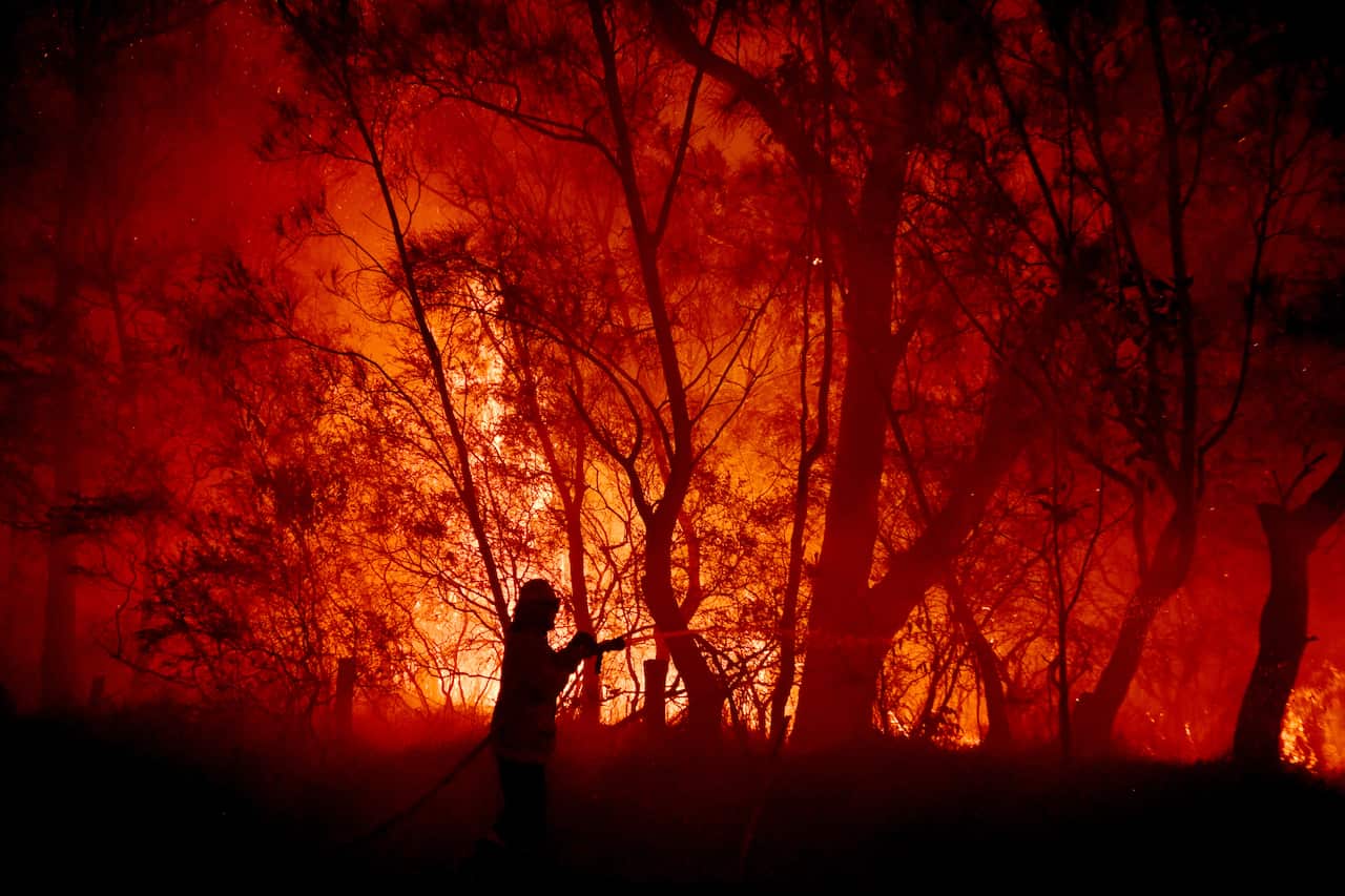 RFS, NSW Fire and Rescue, NPWS officers and local residents fight a bushfire encroaching on properties near Kioloa, between Bateman's Bay and Ulladulla, south of Sydney, Tuesday, December, 3, 2019. (AAP Image/Dean Lewins) NO ARCHIVING