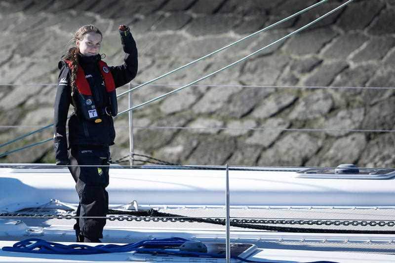 Greta Thunberg waves as she arrives at Santo Amaro Dock, after crossing the Atlantic