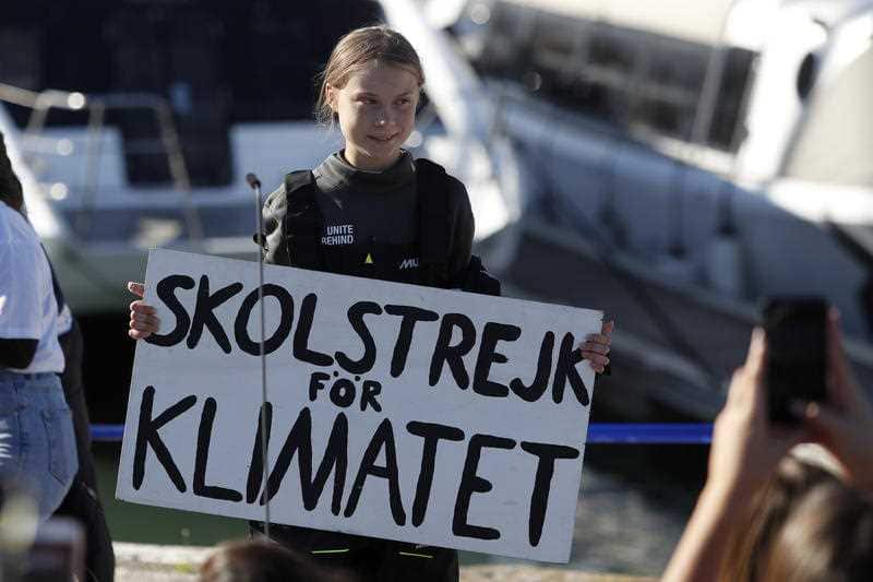 Climate activist Greta Thunberg holds a sign reading 'School strike for the climate' after arriving in Lisbon