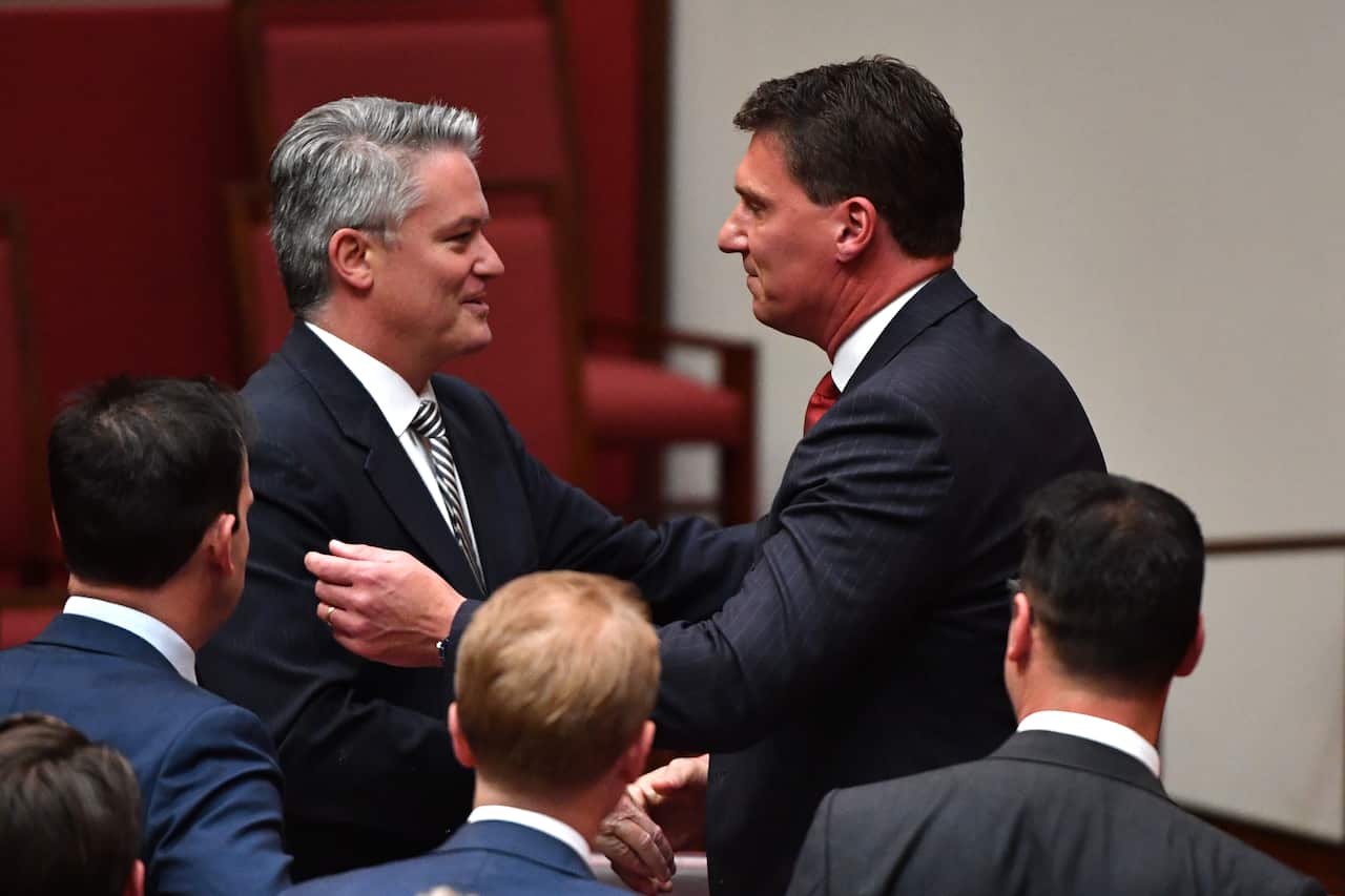 Minister for Finance Mathias Cormann congratulates Independent Senator Cory Bernardi after delivering his valedictory speech in the Senate