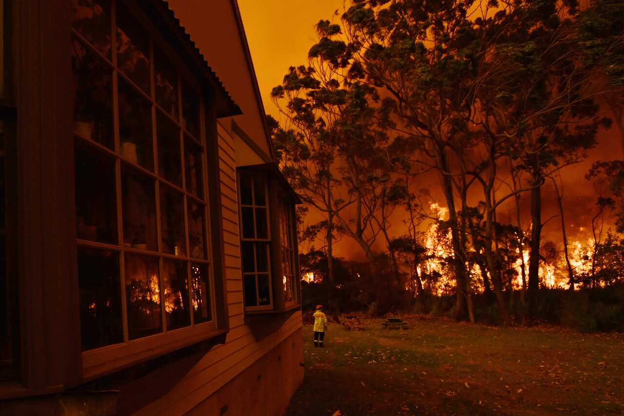 Firefighting crews battle a bushfire encroaching on properties near Lake Tabourie on the Princes Highway between Batemans Bay and Ulladulla. 