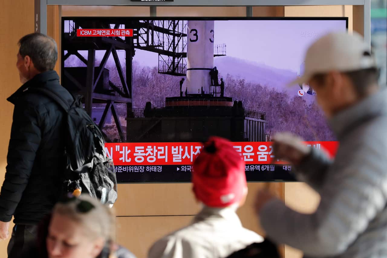 People watch a TV news program reporting North Korea's announcement.