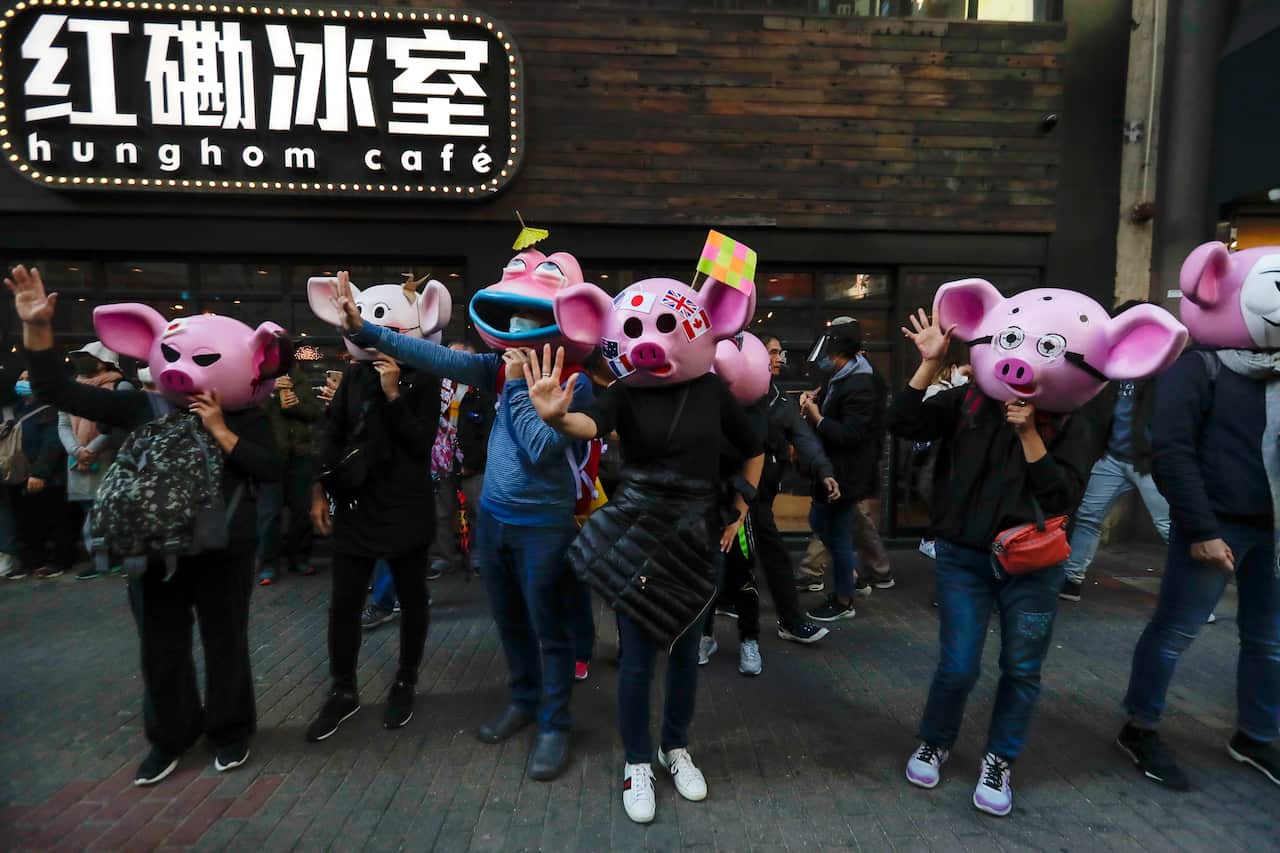 Masked pro-democracy protesters wave as they march on a street in Hong Kong.