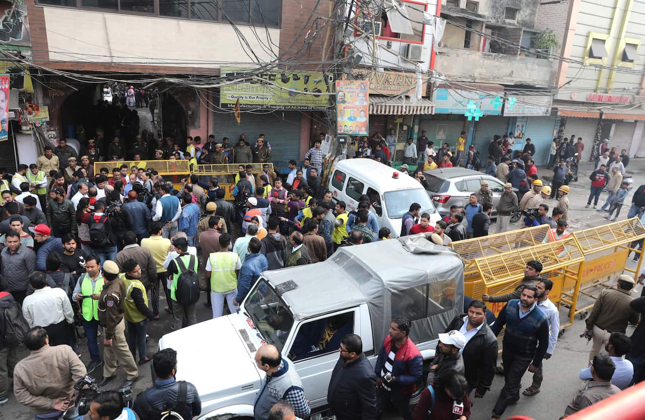 Indian police and journalists stand near the site where a fire broke out in New Delhi, India.
