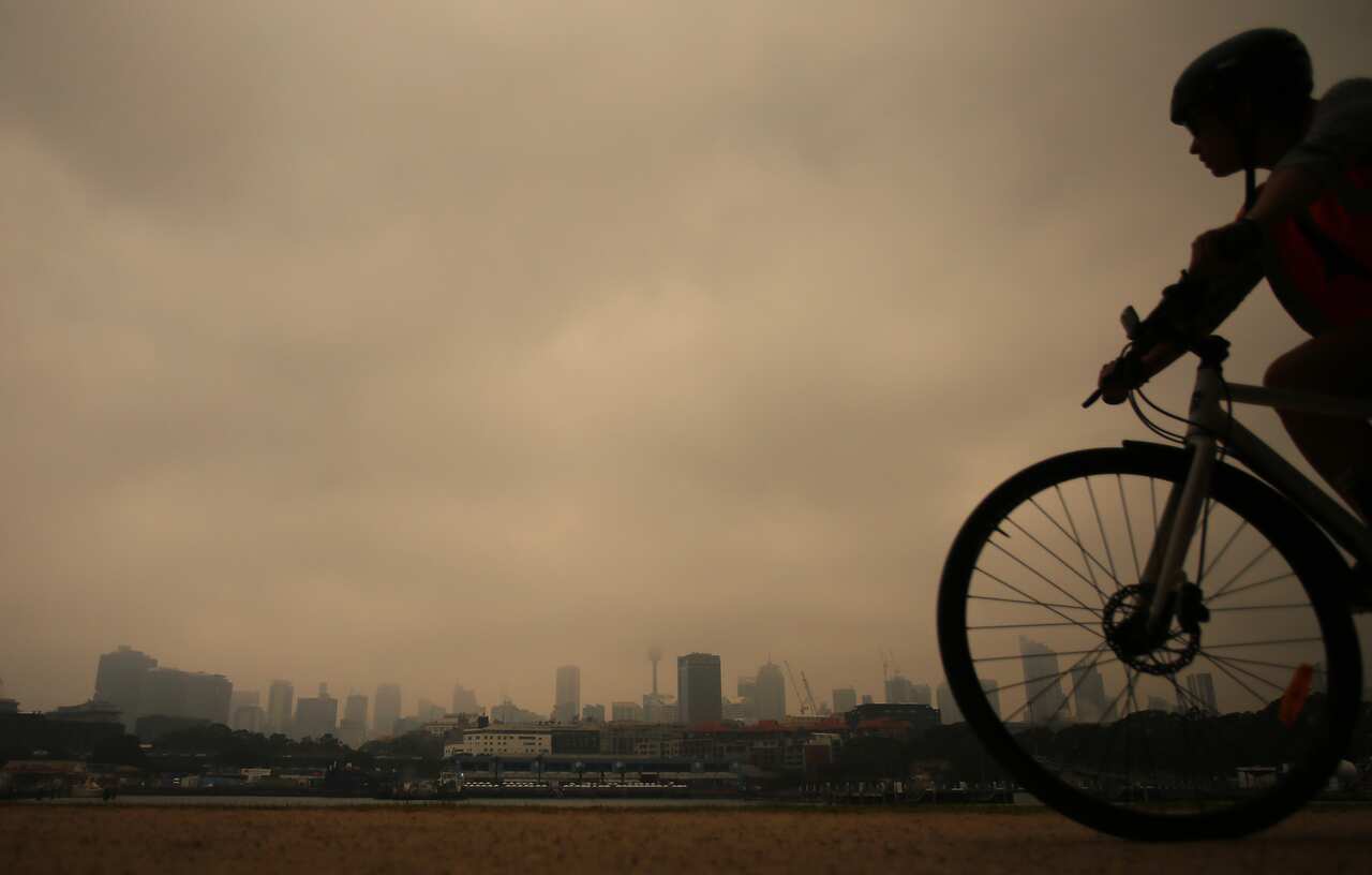 A cyclist rides in Blackwattle bay as smoke haze from bushfires in New South Wales blankets the CBD in Sydney.