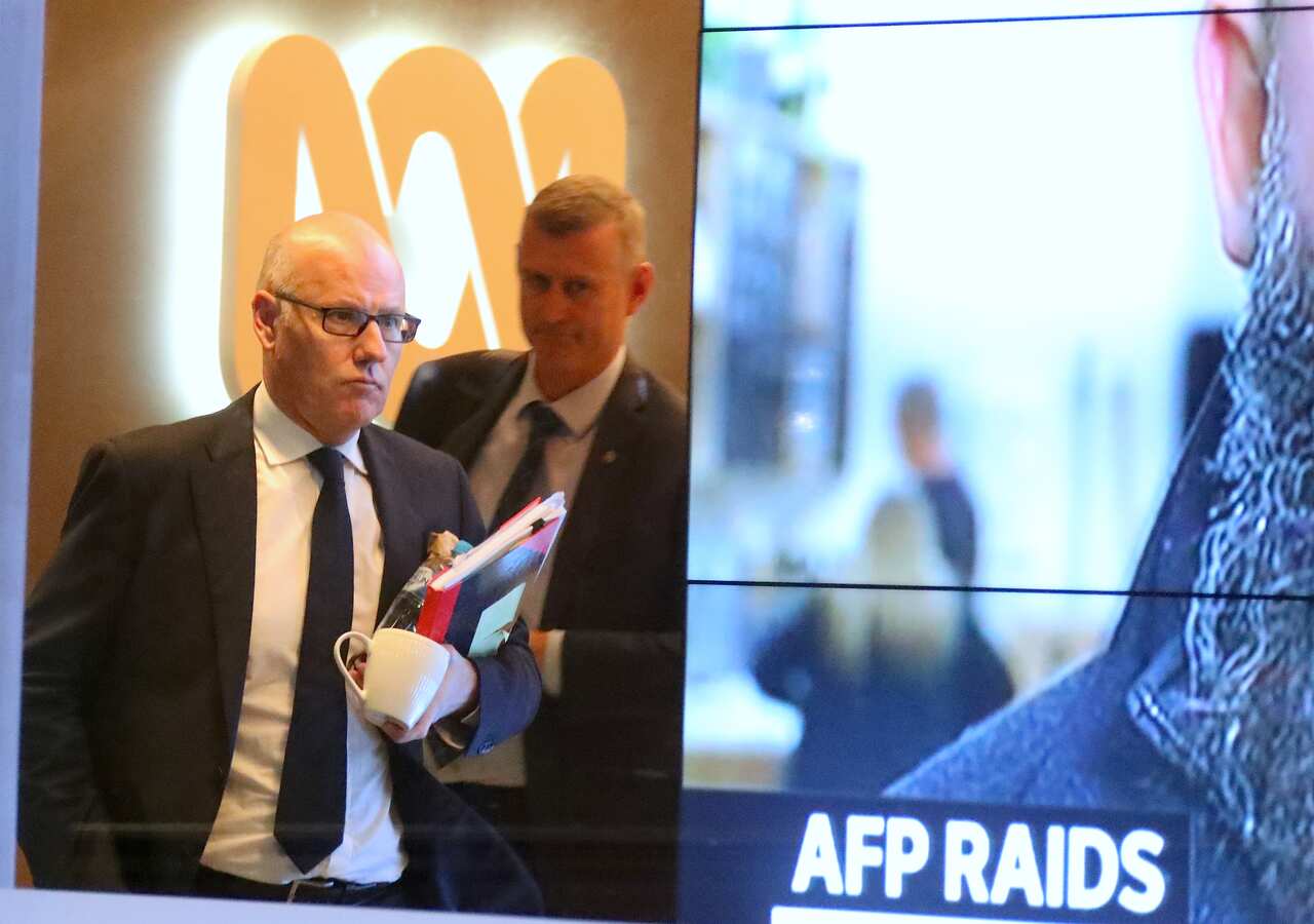 John Lyons (left), Executive Editor of ABC News, is followed by an AFP officer as they walk out the main entrance to the ABC building, Sydney, June 5, 2019. 