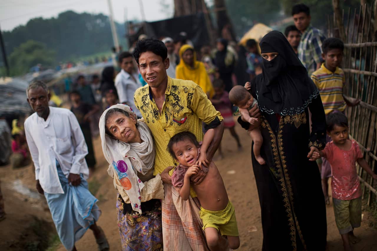 An exhausted Rohingya helps an elderly family member in 2017 as they arrive at refugee camp after crossing from Myanmar to Bangladesh.