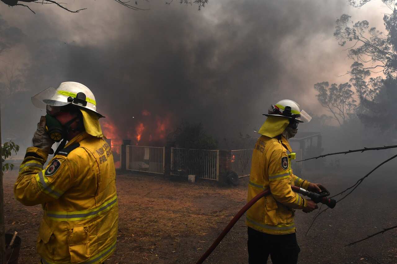 Rural Fire Service crews douse a home lost to the Green Wattle Creek Fire in the south-west of Sydney.