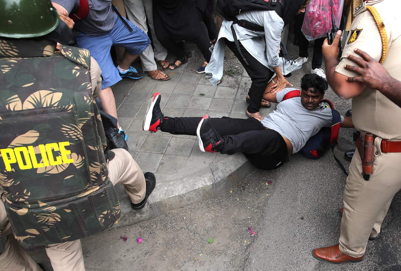 Indian policemen detain protesters during a demonstration.