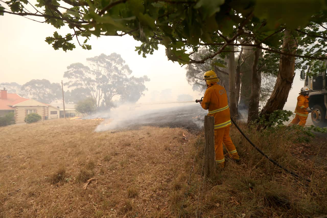 A CFS firefighter gets to work on protecting a home at Woodside in the Adelaide Hills.
