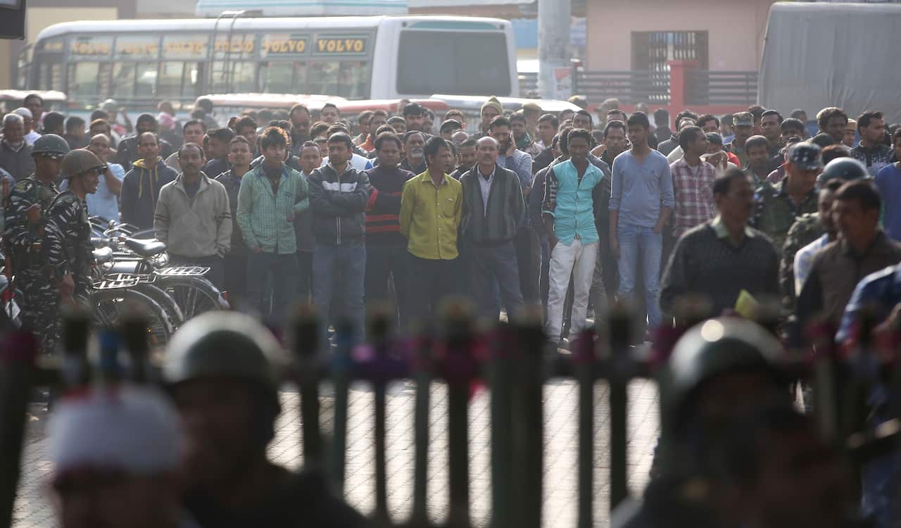 People stand behind a police barricade and watch a protest against the Citizenship Amendment Act in Nalbari, India.