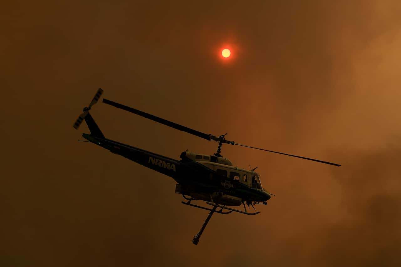 A firefighting helicopter is seen as the Gospers Mountain Fire impacts property at Bilpin.