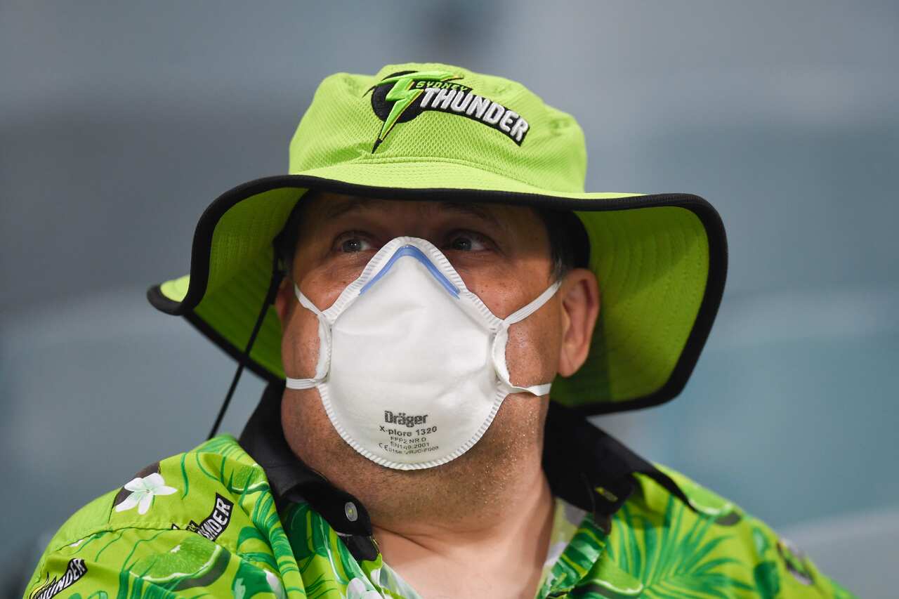A fan wears a face mask as smoke haze forced an end to a Big Bash League cricket match between the Sydney Thunder and the Adelaide Strikers.