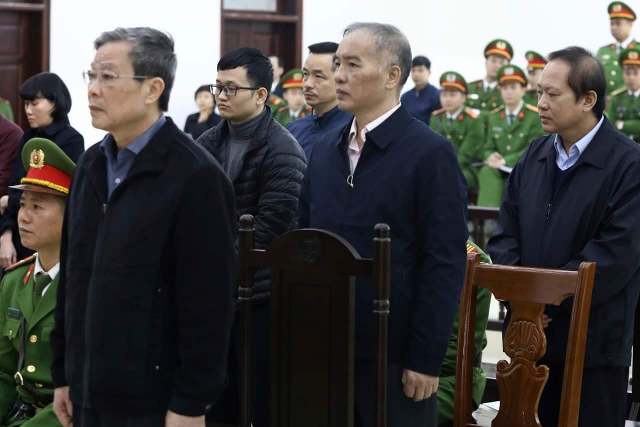Ex-minister of information and communication Nguyen Bac Son (L), stands as the judge reads the verdict.