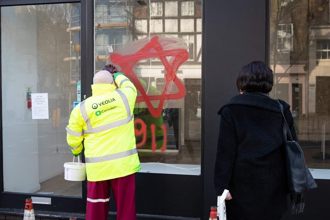 A council cleaner removes the anti-semitic graffiti.