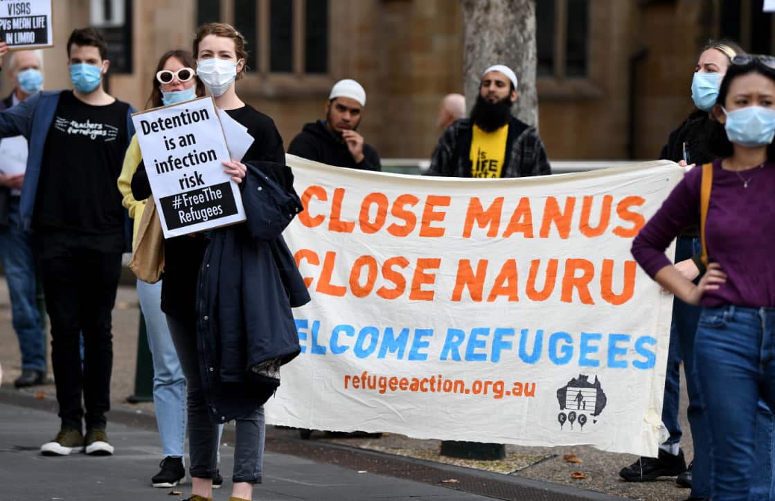 Protesters hold placards during a "Free The Refugees" rally at Sydney Town Hall in Sydney, Saturday, June 13, 2020