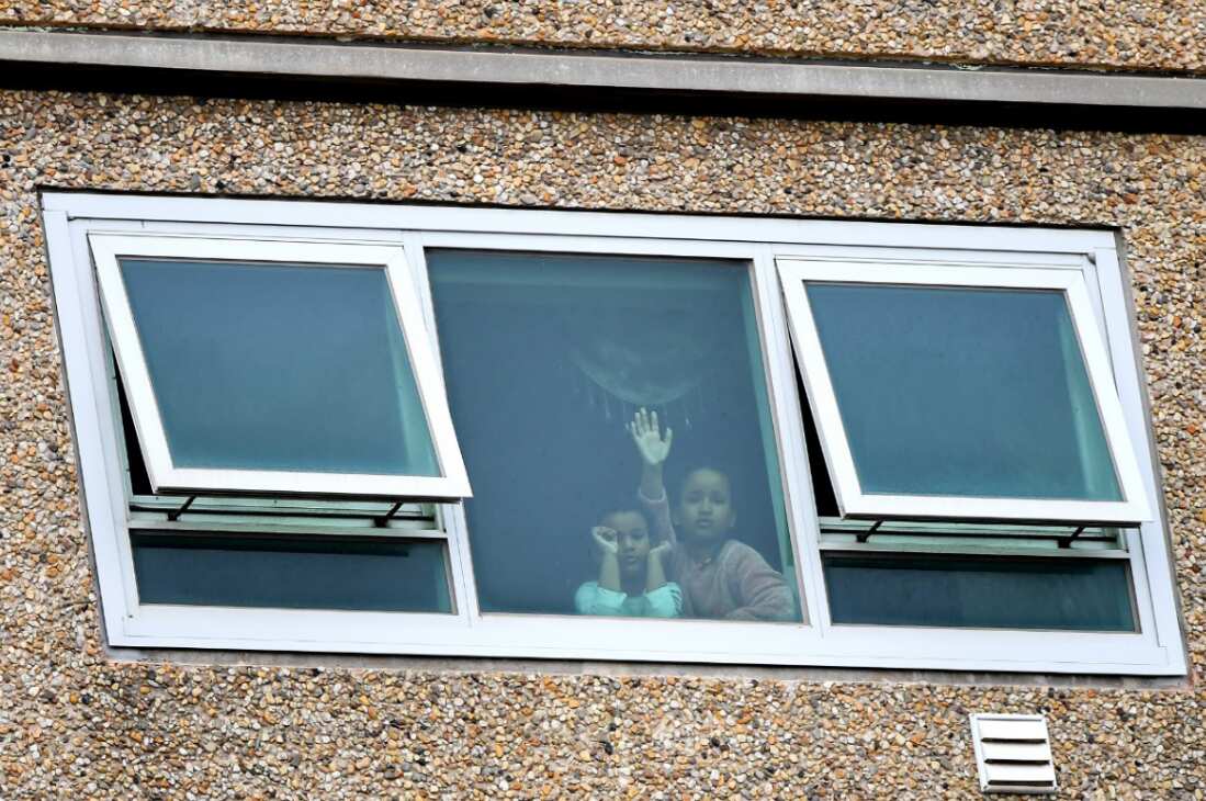 Children from a window inside a unit at the public housing tower along Racecourse Road in Melbourne, Monday, July 6, 2020. 