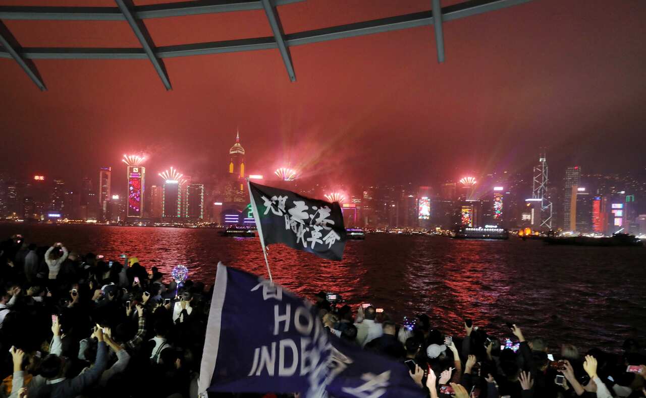 Protesters chant as fireworks explode in Hong Kong along the waterfront on new year's eve in Tsim Sha Tsui in Hong Kong.