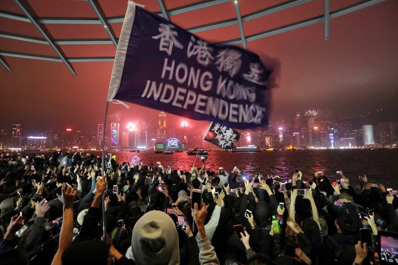 Protesters chant as fireworks explode in Hong Kong along the waterfront on New Year's Eve in Tsim Sha Tsui.