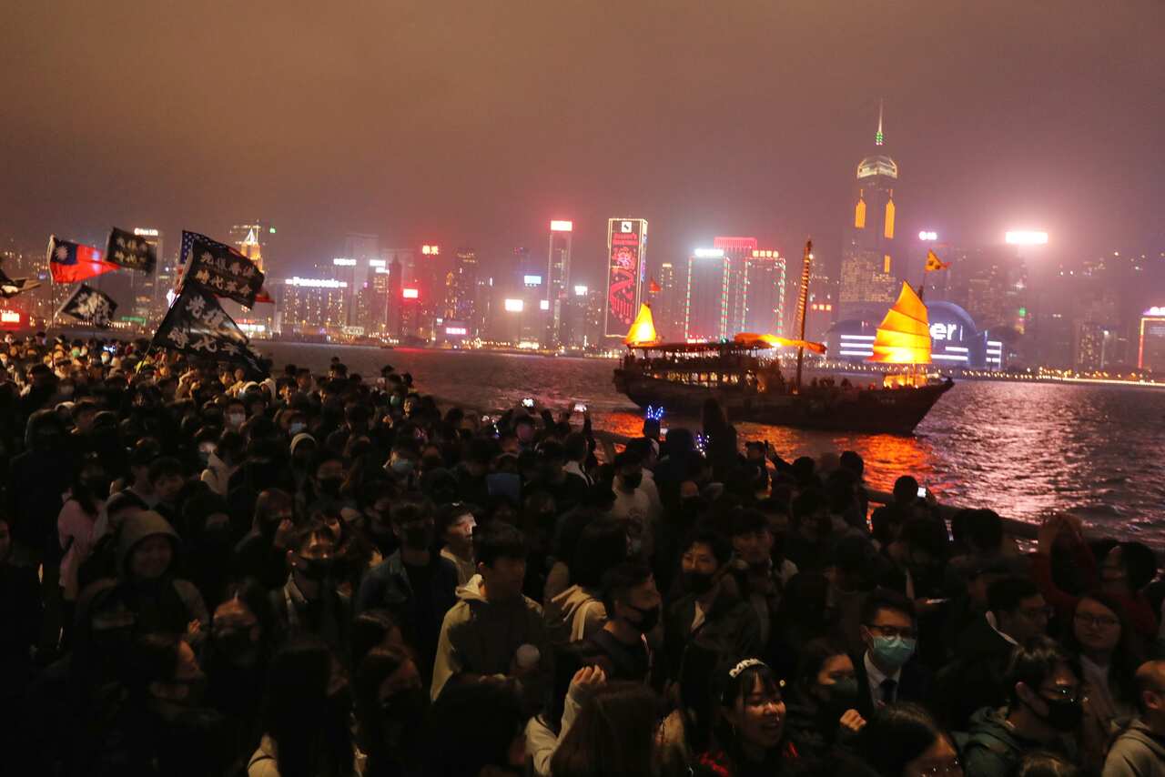 Protesters chant as fireworks explode in Hong Kong along the waterfront on new year's eve in Tsim Sha Tsui in Hong Kong.