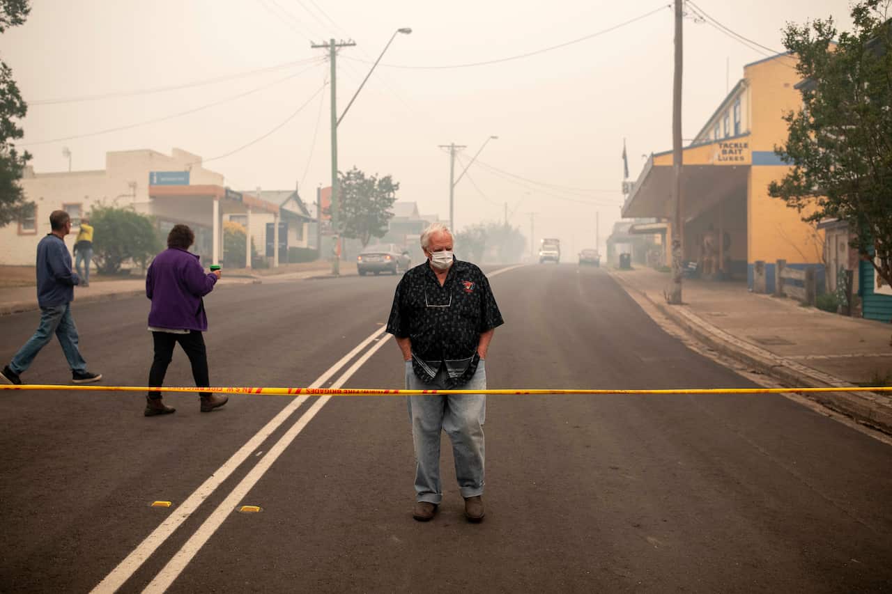 A Cobargo resident looks at destroyed buildings in Cobargo, NSW, Wednesday, January 1, 2020. Several bushfire-ravaged communities in NSW have greeted the new year under immediate threat. (AAP Image/Sean Davey) NO ARCHIVING